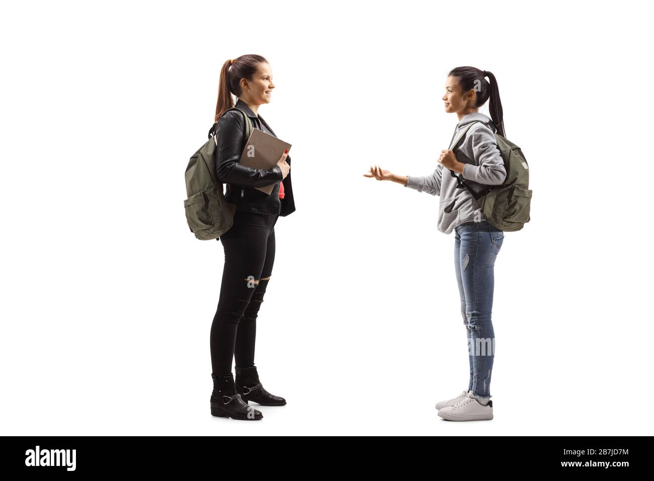 Foto di profilo a tutta lunghezza di due studenti femminili che hanno una conversazione isolata su sfondo bianco Foto Stock
