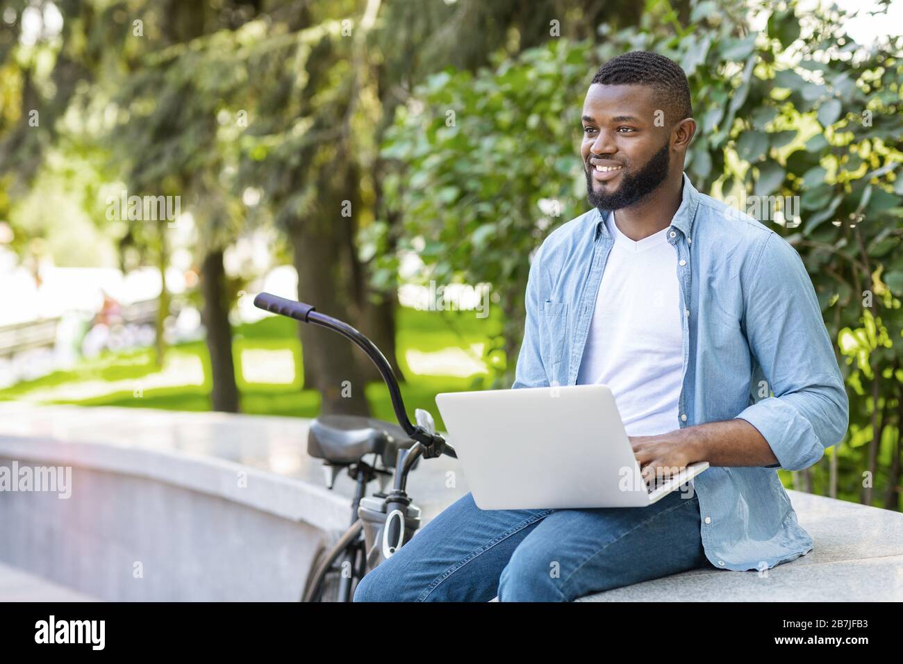 Bell'imprenditore afro-americano che lavora su laptop all'aperto Foto Stock