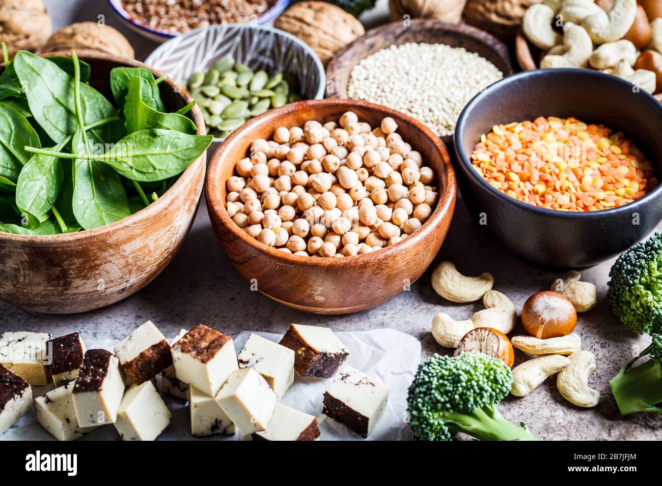 Fonti vegane di background proteico. Tofu, ceci, lenticchie, noci, spinaci e broccoli sono proteine vegetali. Foto Stock