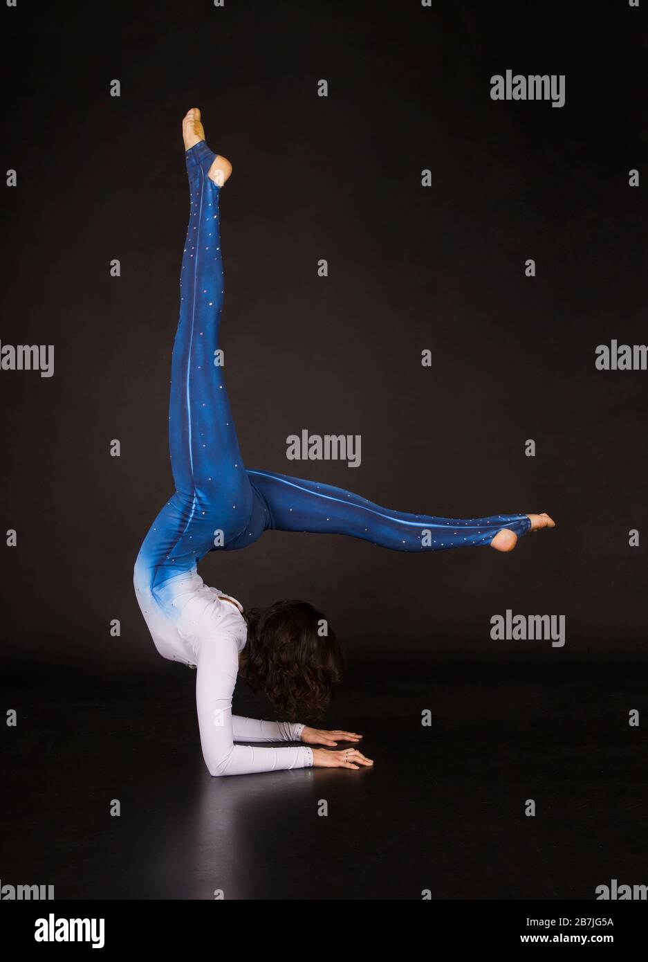 donna acrobata, ginnastica, giovane atleta in tuta bianca e blu, pratica acrobatica. Foto Stock