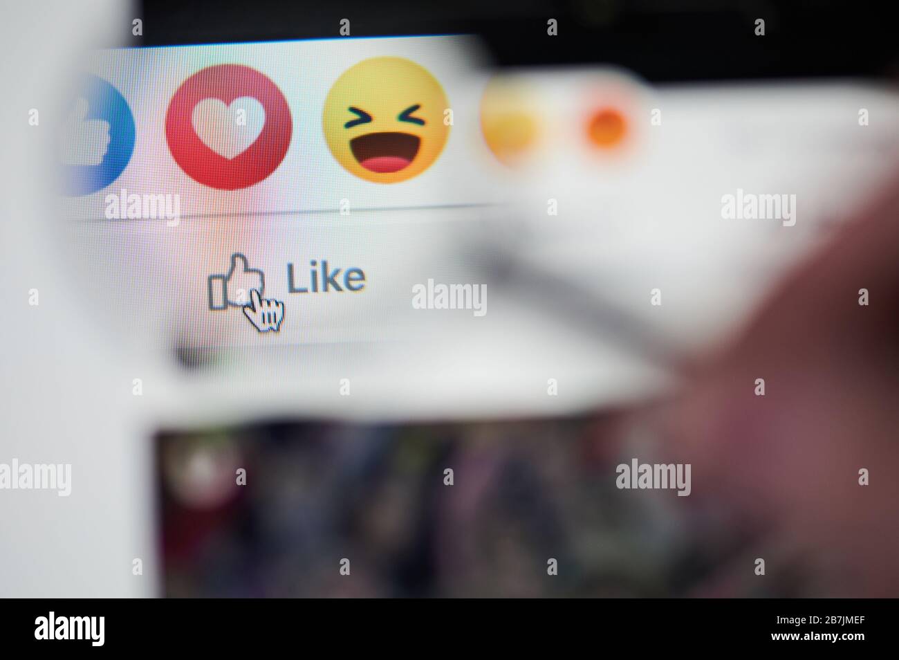 New-York , USA - 13 marzo 2020: React on facebook post su laptop close up view throw lente di ingrandimento Foto Stock