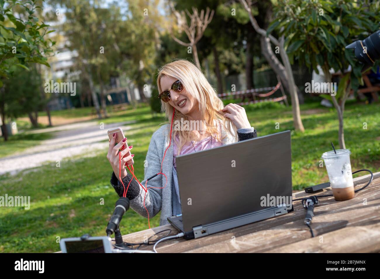 Blogger femmina bionda che interagisce con il suo mobile - lavorare all'aperto - viaggiare il mondo - youtubers e influenzatori concetto di lavoro Foto Stock