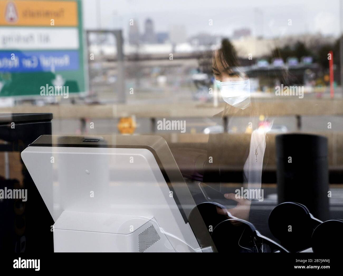 Newark, Stati Uniti. 16 Marzo 2020. Una donna indossa una maschera facciale mentre lavora con un chiosco per il check-in all'aeroporto internazionale di Newark a Newark, NJ, lunedì 16 marzo 2020. New Jersey Gov. Phil Murphy lunedì ha esortato i residenti a rimanere a casa dopo le 8 e ha attivato la Guardia Nazionale. Inoltre ha emesso un ordine esecutivo che limita alcune operazioni di affari per combattere la diffusione di coronavirus. Foto di John Angelillo/UPI Credit: UPI/Alamy Live News Foto Stock