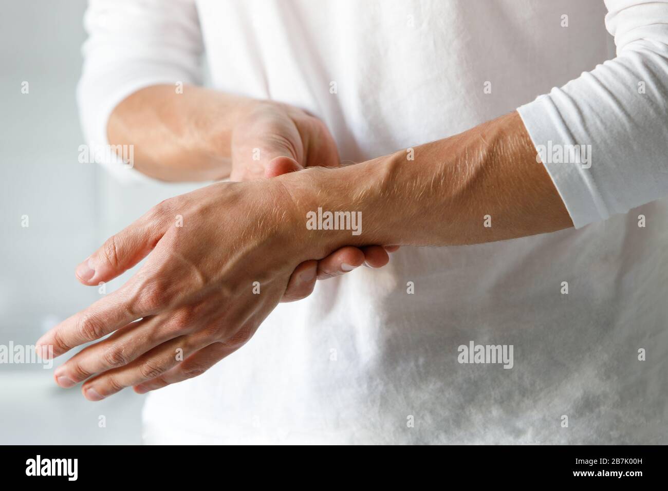 Closeup di braccia maschili che tiene il suo polso doloroso causato da un lavoro prolungato sul computer, laptop. Sindrome del tunnel carpale, artrite, disea neurologica Foto Stock