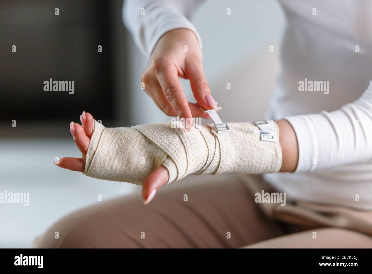 Primo piano della donna che avvolge il suo polso doloroso con bendaggio ortopedico elastico di supporto flessibile dopo sport o lesioni non riusciti. Tunnel carpale sy Foto Stock