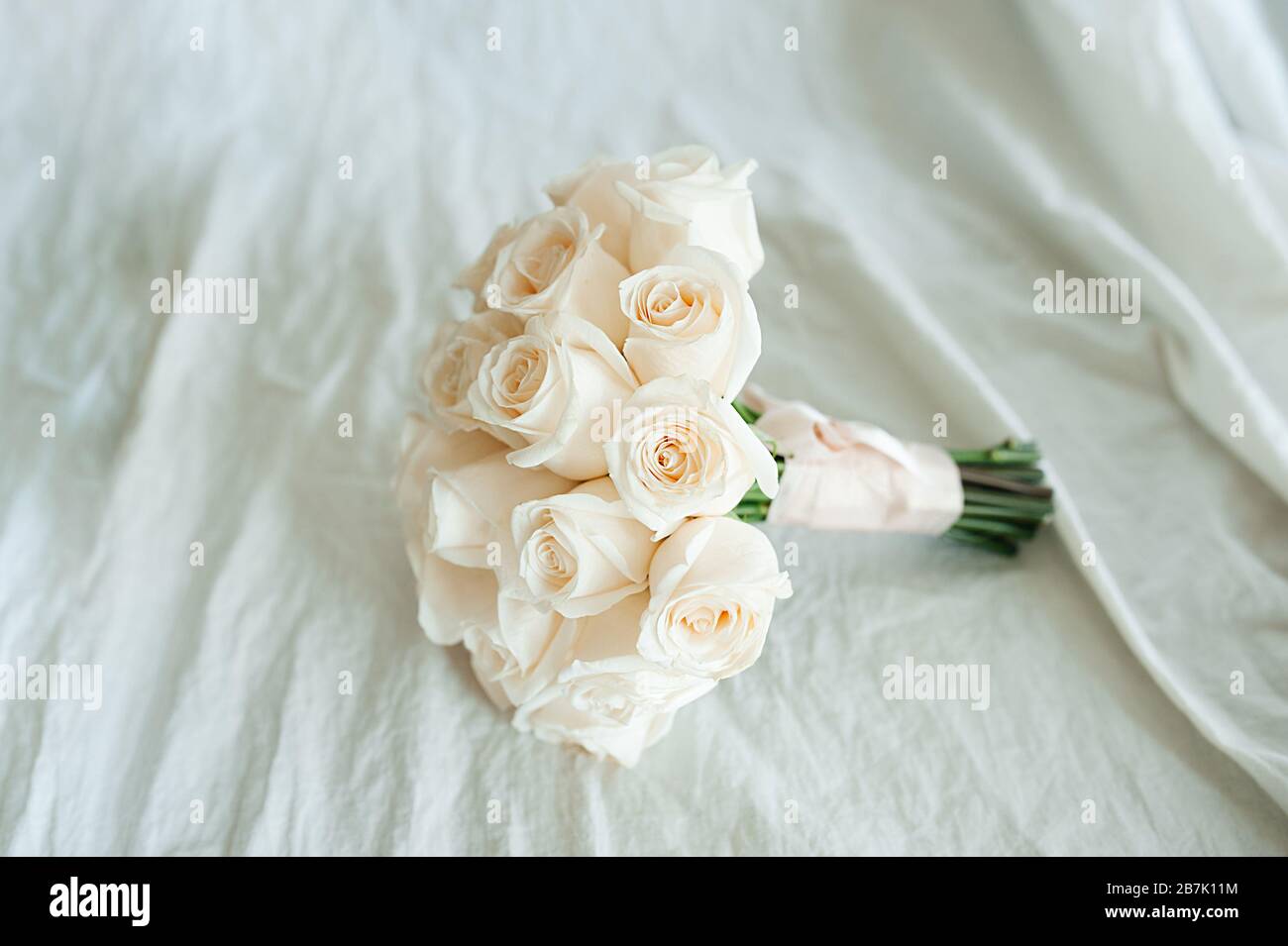 mazzo di nozze di rose bianche fresche identiche su un tessuto di cotone sbriciolato di colore lattiginoso. La vista dall'alto. Spazio per testo, layout per inv Foto Stock