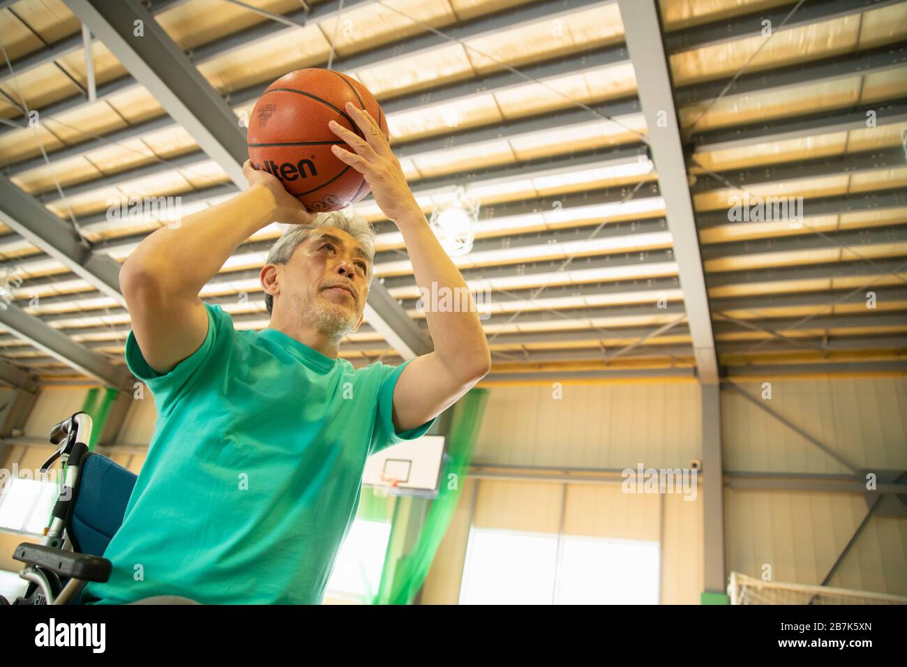 Uomo anziano in sedia a rotelle tiro basket ball Foto Stock
