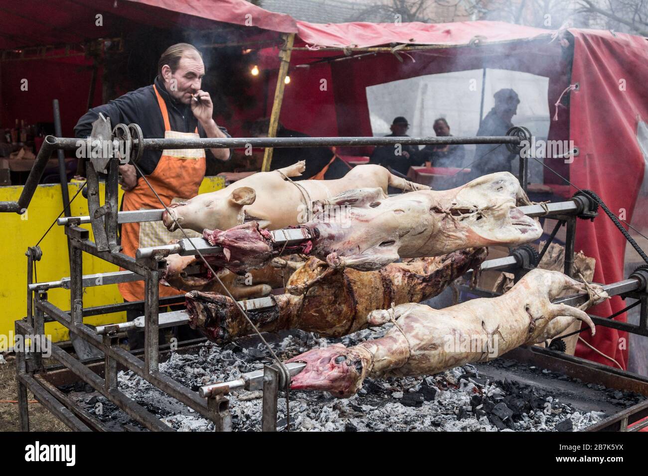 KACAREVO, SERBIA - 18 FEBBRAIO 2017: Uomo Roasting un maiale e un agnello, su una griglia tradizionale della Serbia, nei Balcani, chiamato Pecenje su un mercato. Por Foto Stock