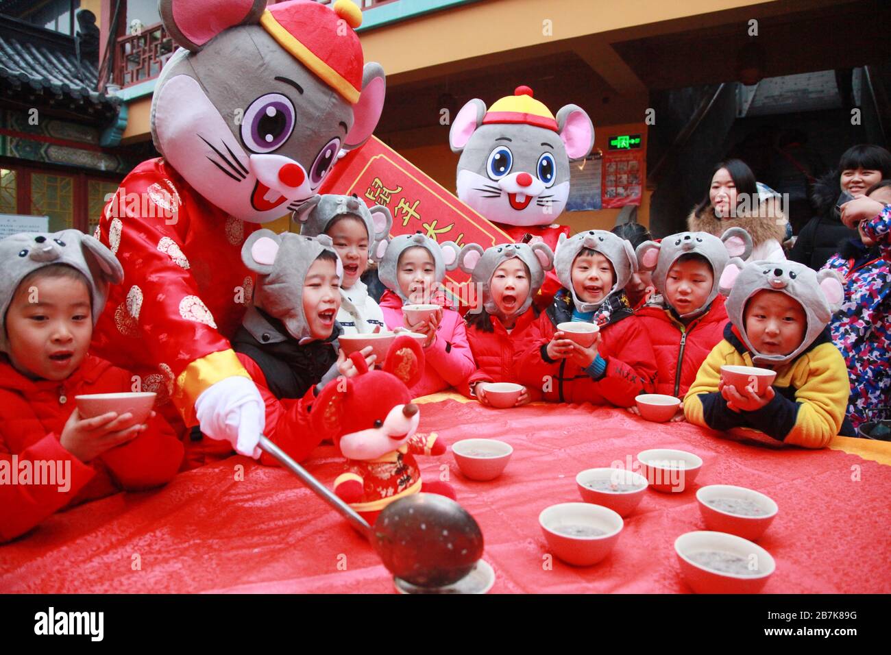 I bambini che indossano i copricapo del mouse si allineano per il porridge del riso per abbracciare il nuovo anno al Tempio di Xuanzang il giorno di Laba nella città di Nanjing, pr Jiangsu della Cina orientale Foto Stock