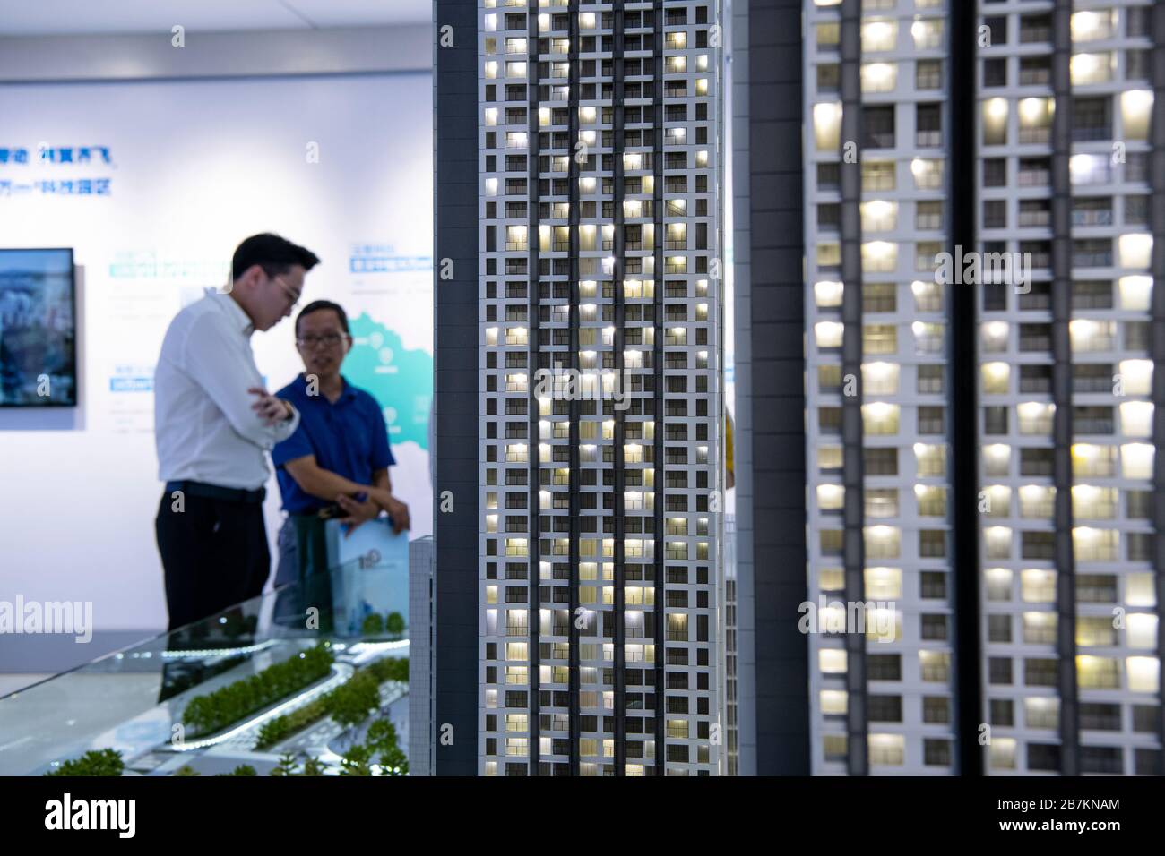 Foto creativa: In questa foto non localizzata, i clienti osservano modelli di edifici e appartamenti, considerando quale sia la casa giusta per loro, in un Foto Stock