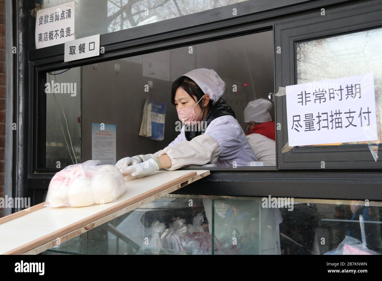 Un negozio di bun al vapore crea 'no touch selling' utilizzando un asse per consegnare buns e codice QR per raccogliere la tassa per evitare la trasmissione di virus, Pechino Foto Stock