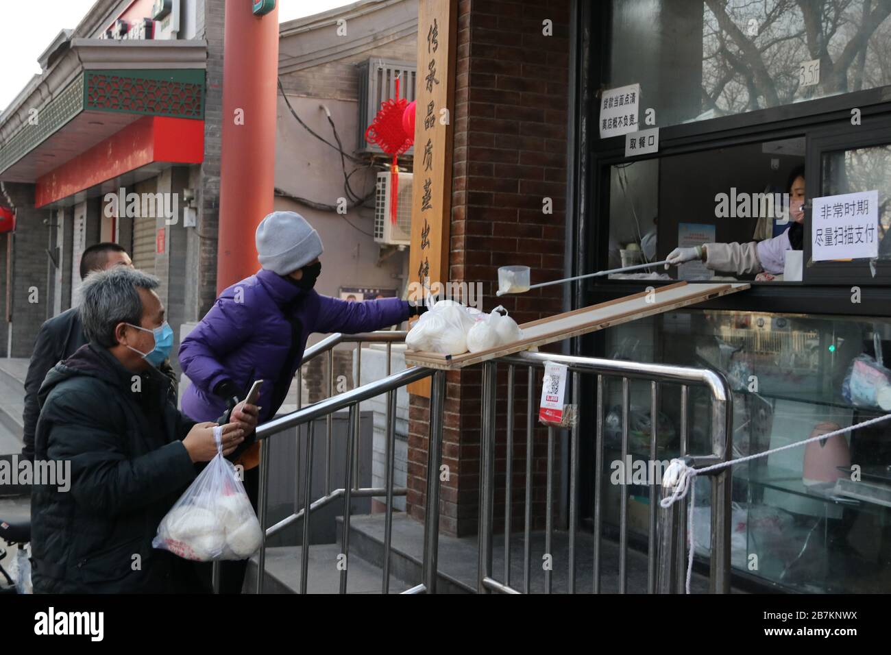 Un negozio di bun al vapore crea 'no touch selling' utilizzando un asse per consegnare buns e codice QR per raccogliere la tassa per evitare la trasmissione di virus, Pechino Foto Stock