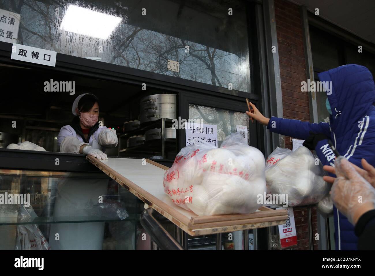 Un negozio di bun al vapore crea 'no touch selling' utilizzando un asse per consegnare buns e codice QR per raccogliere la tassa per evitare la trasmissione di virus, Pechino Foto Stock