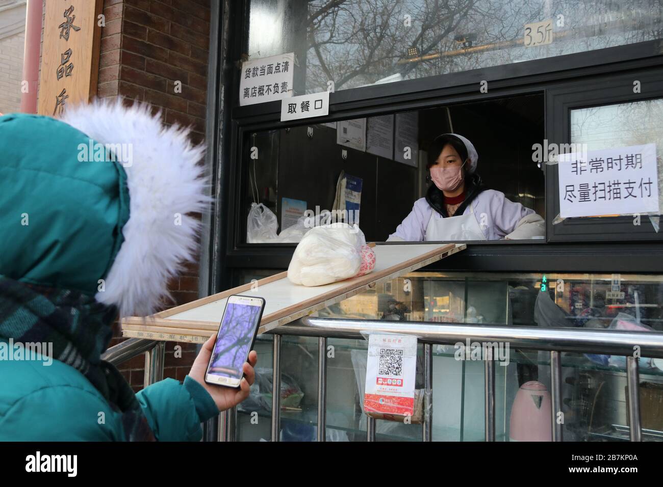 Un negozio di bun al vapore crea 'no touch selling' utilizzando un asse per consegnare buns e codice QR per raccogliere la tassa per evitare la trasmissione di virus, Pechino Foto Stock