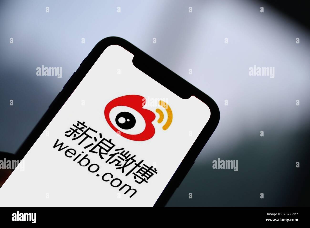 Foto creativa: Il logo di Sina Weibo, un sito web cinese di microblogging (weibo) simile a Twitter, è mostrato su uno smartphone come il proprietario lo sta utilizzando, Foto Stock