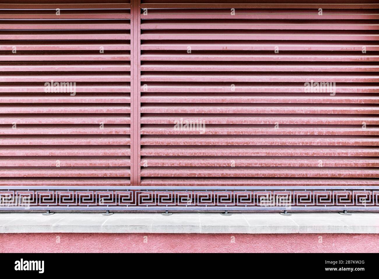 tende orizzontali rosse metallizzate e ringhiere in metallo battuto decorative. sfondo moderno dell'edificio Foto Stock