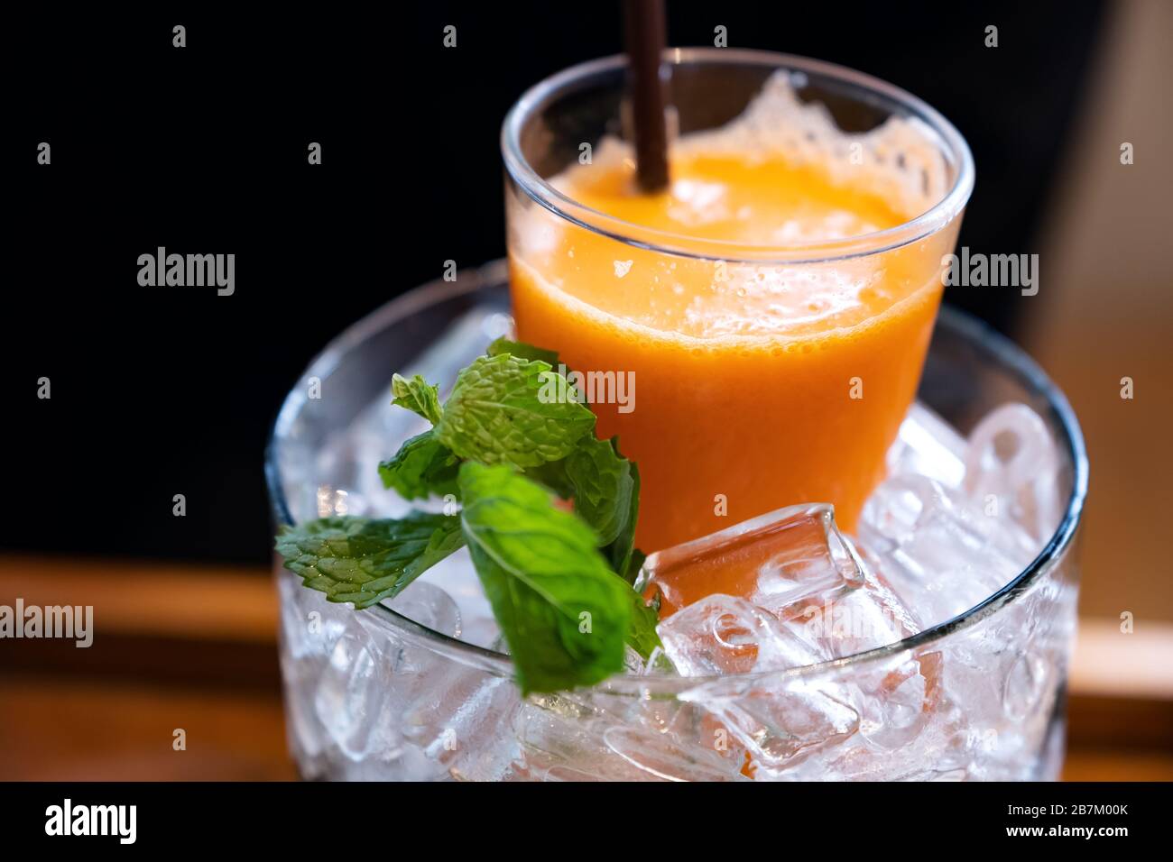 Un bicchiere di succo misto di arancia e carota in un vaso di ghiaccio con foglie di menta Foto Stock