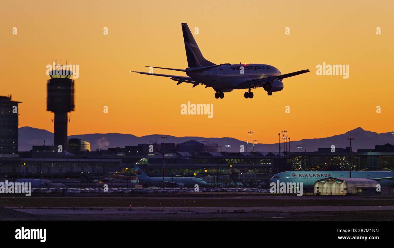 Richmond, British Columbia, Canada. 16 Marzo 2020. Lunedì 16 marzo 2020 atterra un jet WestJet Airlines Boeing 737-600 (C-GWCQ) al tramonto, all'aeroporto internazionale di Vancouver, a Richmond, B.C., Canada. All'inizio del giorno il governo canadese, nel tentativo di fermare la diffusione del romanzo coronavirus, ha annunciato che i confini della nazione sarebbero stati chiusi a partire da mercoledì 18 marzo a tutti i viaggiatori diversi dai cittadini canadesi e residenti permanenti, cittadini statunitensi, diplomatici e lavoratori essenziali. Credit: Bayne Stanley/ZUMA Wire/Alamy Live News Foto Stock