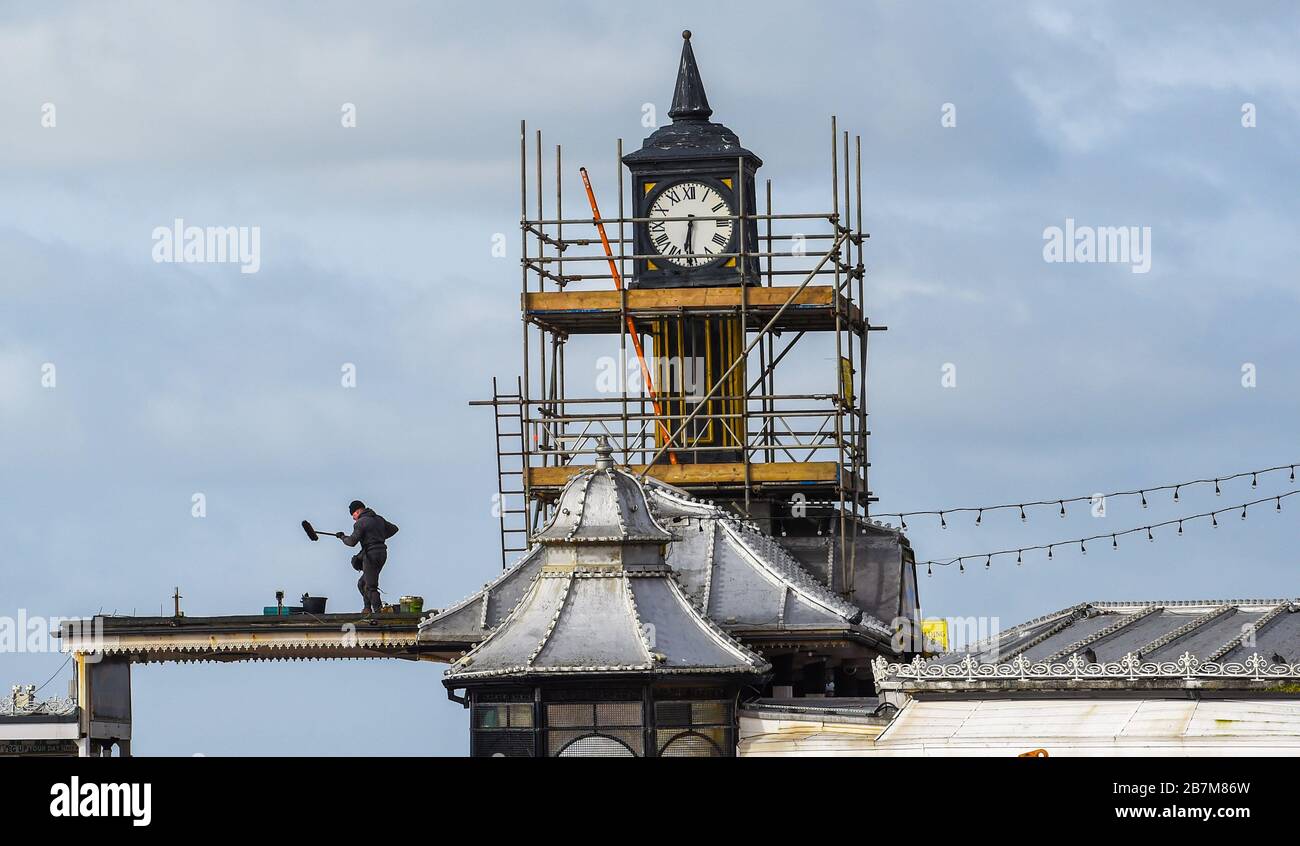 Brighton UK 9th Marzo 2020 - un membro del personale lavora sul tetto del Brighton Palace Pier in una luminosa giornata di sole mentre il tempo più caldo è previsto per i prossimi due giorni nel sud-est della Gran Bretagna : Credit Simon Dack / Alamy Live News Foto Stock