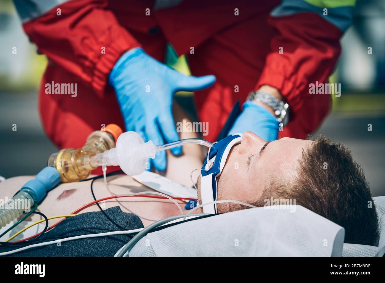 Paramedico del servizio medico di emergenza che aiuta l'uomo dopo la rianimazione cardiopolmonare. Temi aiutare, speranza di un'assistenza sanitaria. Foto Stock