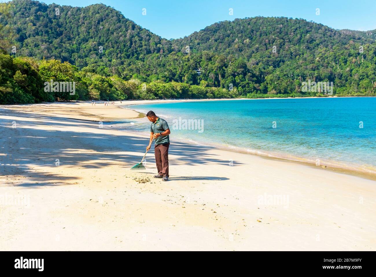 Uomo che rastrella e pulisce la spiaggia ad Andaman, Langkawi, Malesia, Asia Foto Stock