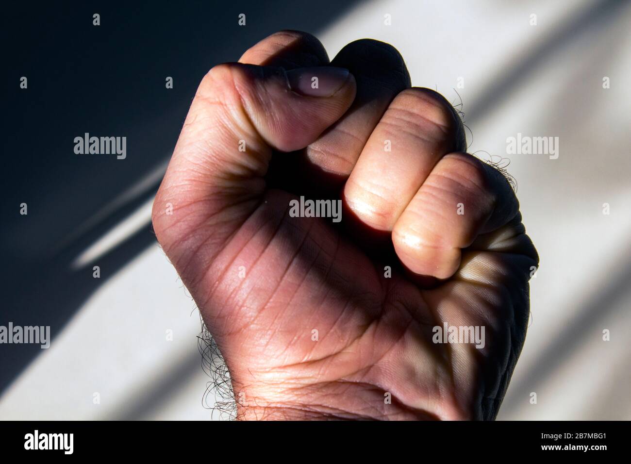 Primo piano della mano sinistra di un uomo medio-orientale, fiestato, nell'ombra. Foto Stock