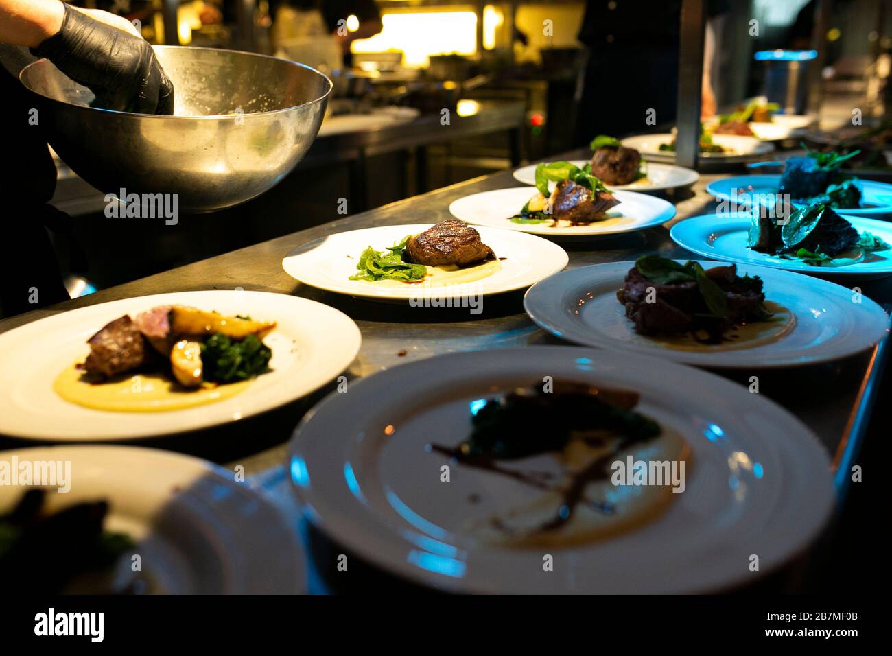 Chef che aggiunge alcune verdure su un pezzo di carne durante la sua preparazione Foto Stock