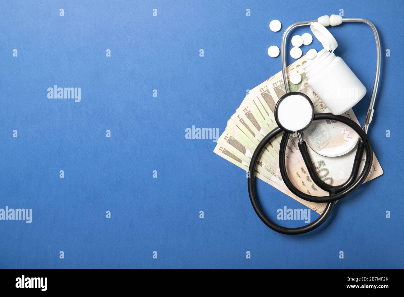 Vaso con pillole e uno stetoscopio su sfondo blu. Il concetto di medicina e salute. Prezzi dei farmaci più alti. Politica e salute Foto Stock