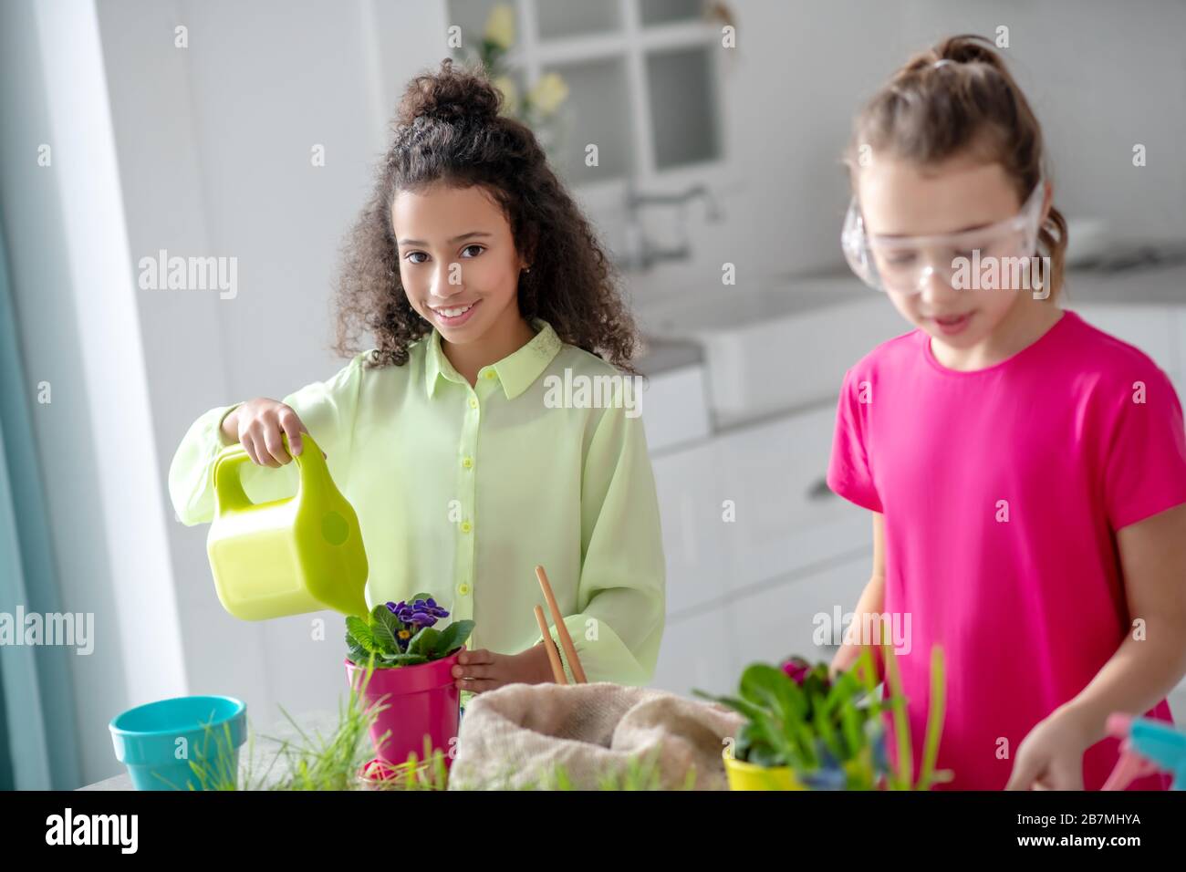 Nelle vicinanze si trovano una ragazza dalla pelle scura con una lattina d'acqua, una ragazza dalla pelle discreta. Foto Stock