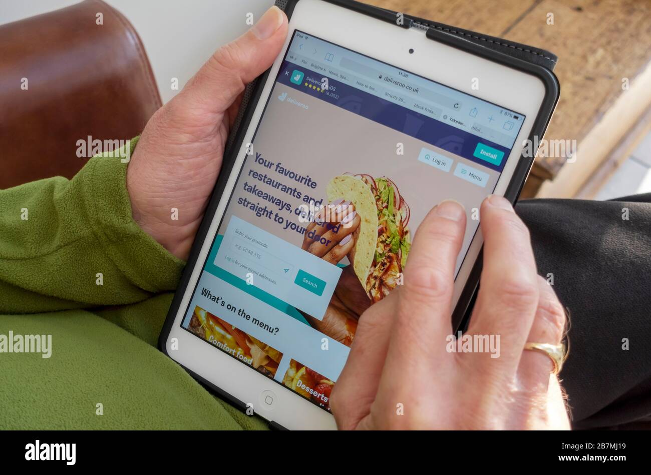 Primo piano di persona uomo che ordina un ordine di fast food online sul sito web Deliveroo su iPad tablet Inghilterra Regno Unito Foto Stock