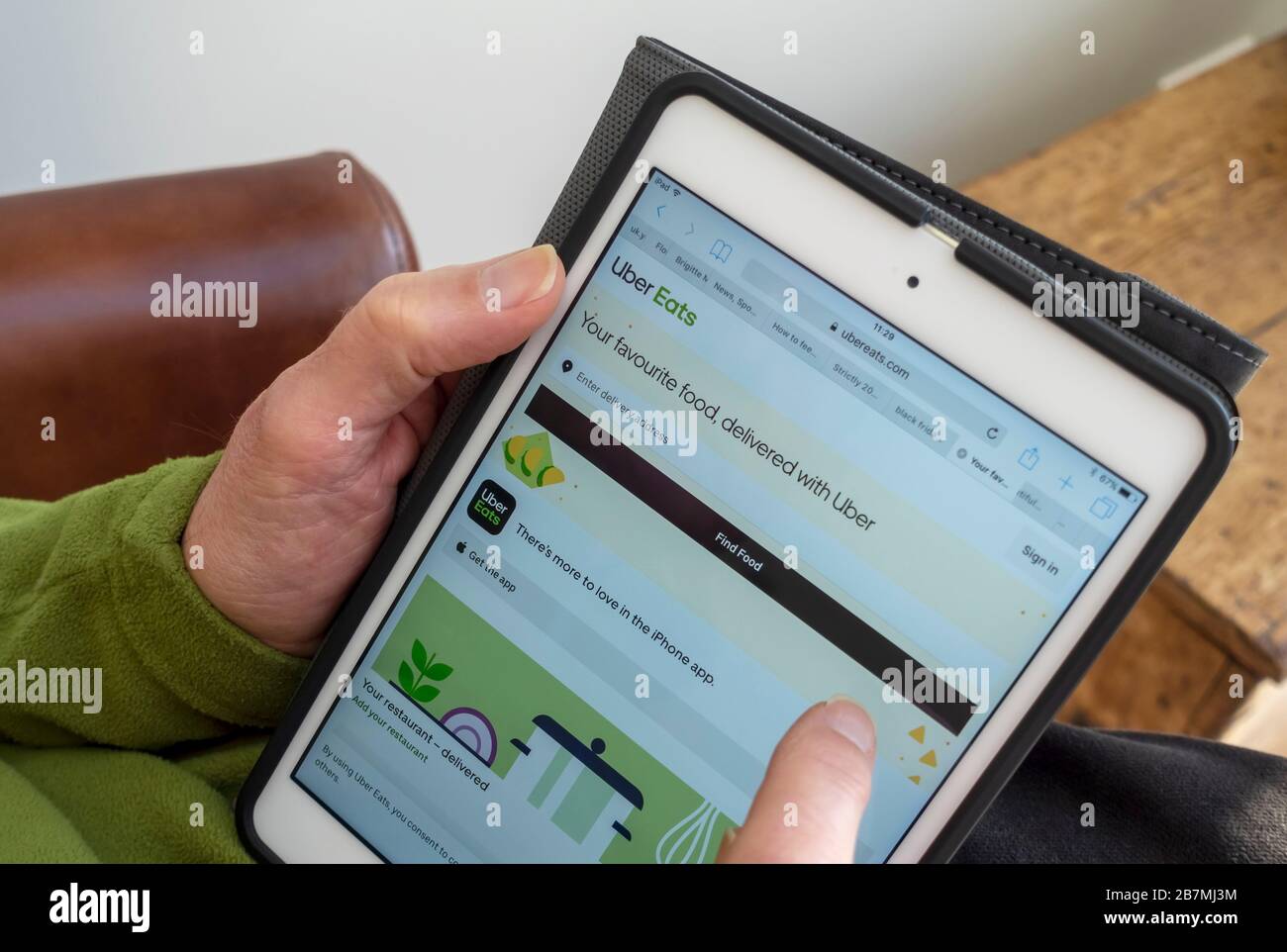 Primo piano di persona uomo cercando e ordinare online da Uber eats takeaway sito web su iPad tablet Inghilterra Regno Unito GB Gran Bretagna Foto Stock