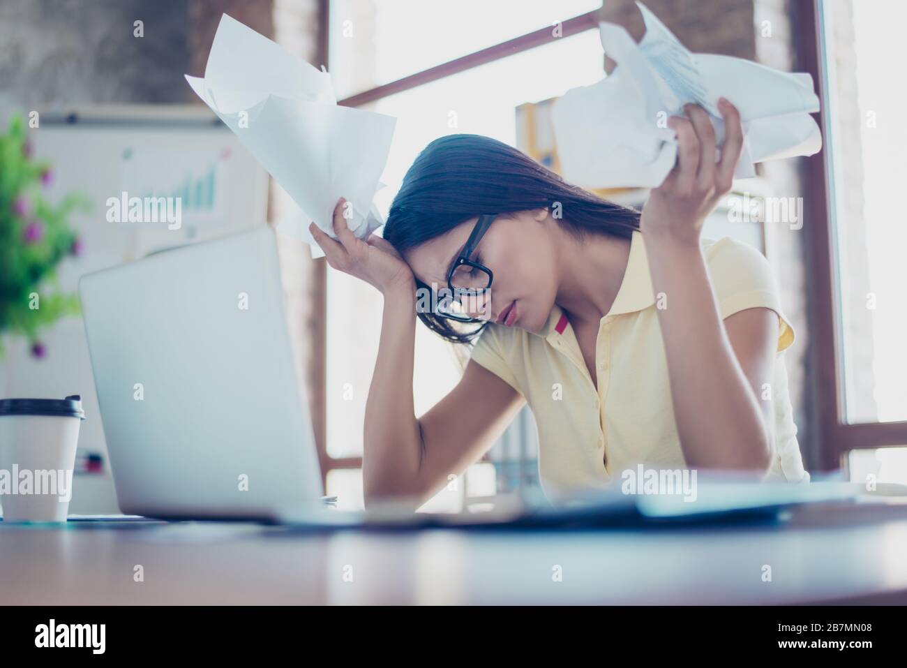 Giovane donna d'affari graziosa è vestiti casual e gli occhiali è stanco dal lavoro in ufficio, carta sbriciolante Foto Stock