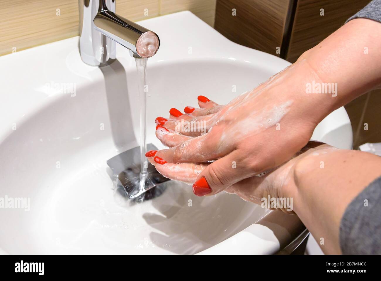 Una donna sta insaponando le sue mani con sapone sotto l'acqua corrente Foto Stock