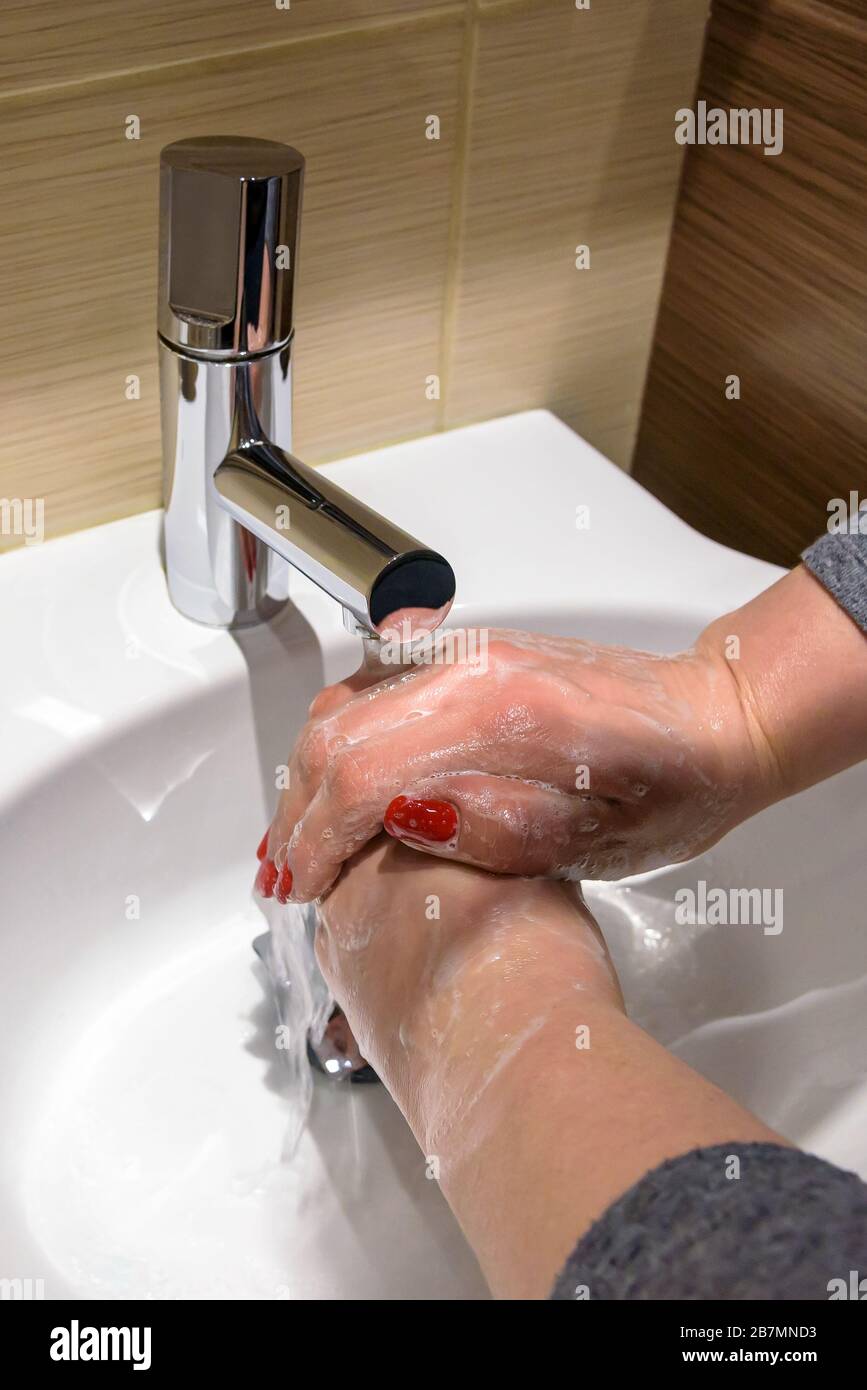 Una donna sta insaponando le sue mani con sapone sotto l'acqua corrente Foto Stock