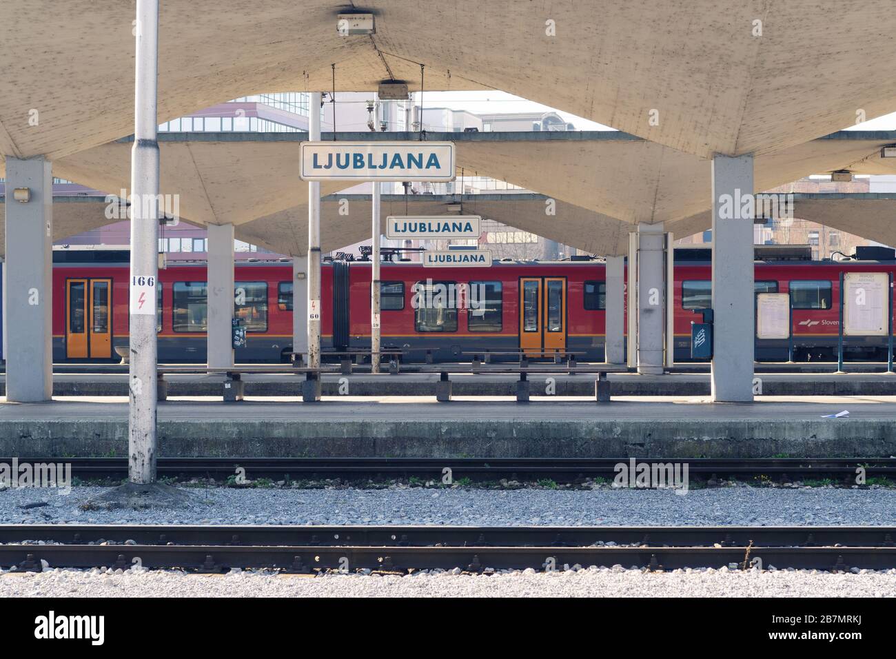 Lubiana, Slovenia - 17 marzo 2020: Piatto vuoto nella stazione ferroviaria di Lubiana con panchine e treno liberi durante l'epidemia di Coronavirus Covid-19 Foto Stock