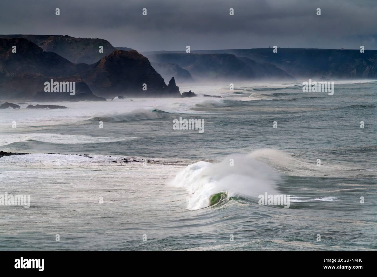 Vista panoramica della costa lungo la spiaggia di Amado (Praia do Amado) con grandi onde durante una tempesta, in Algarve, Portogallo Foto Stock
