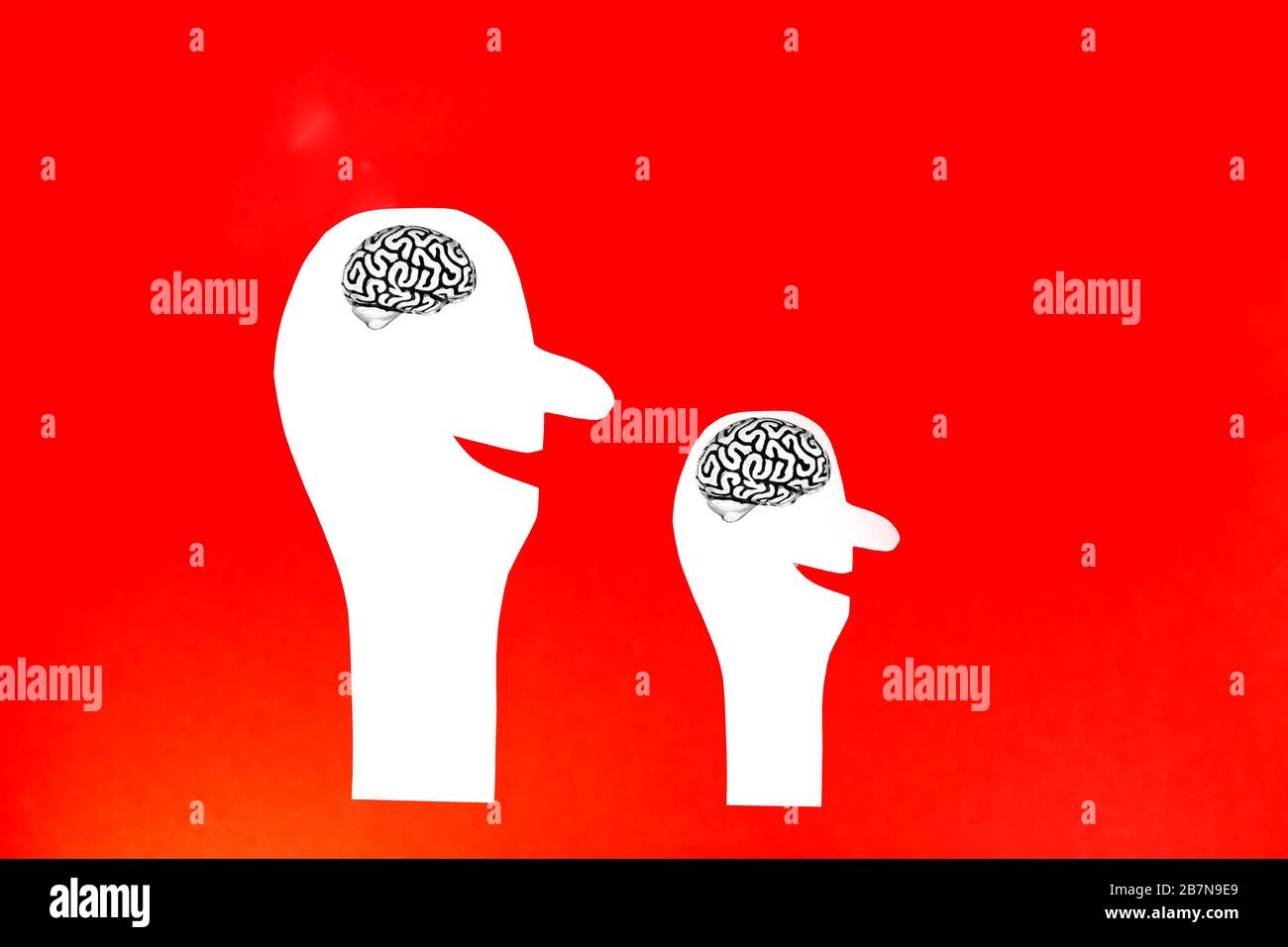 Due silhouette di una persona sorridente tagliate in carta bianca con un modello in metallo di un cervello umano all'interno della testa su uno sfondo rosso. Foto Stock