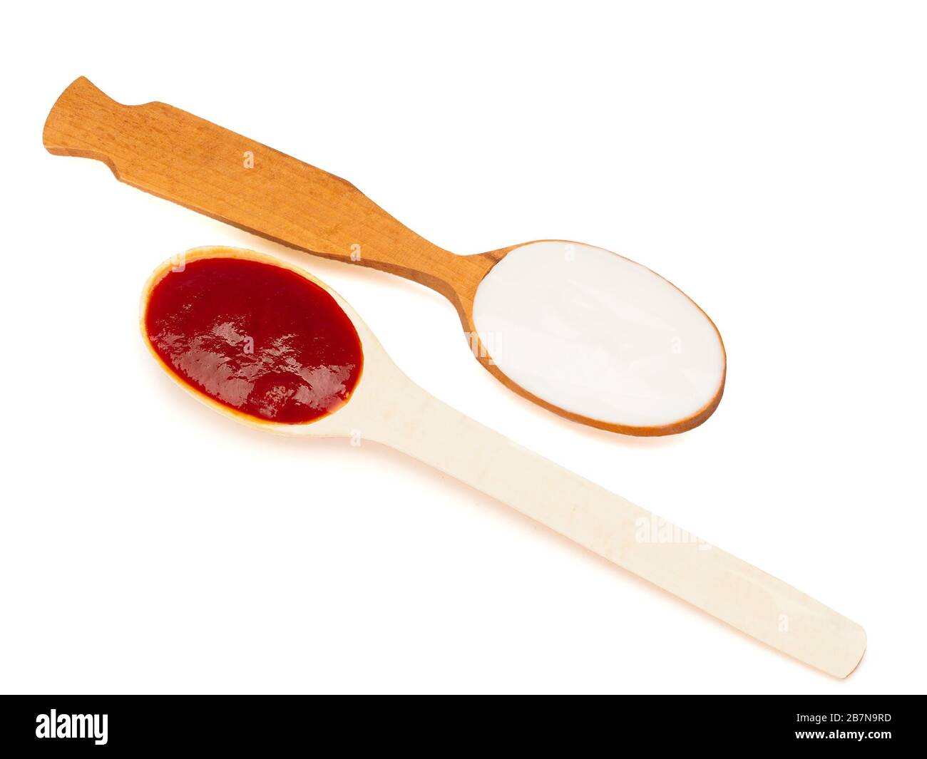 Yogurt liquido e ketchup nei cucchiai di legno Foto Stock