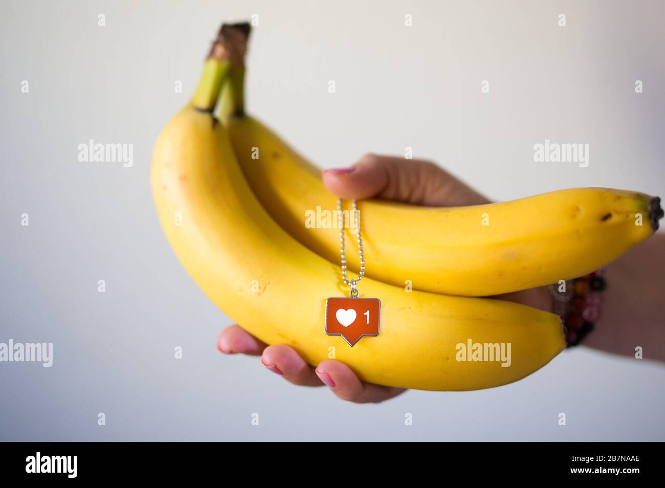 Banana fresca e arancione tenere in mano e social media instagram come, l'icona amore. Foto Stock