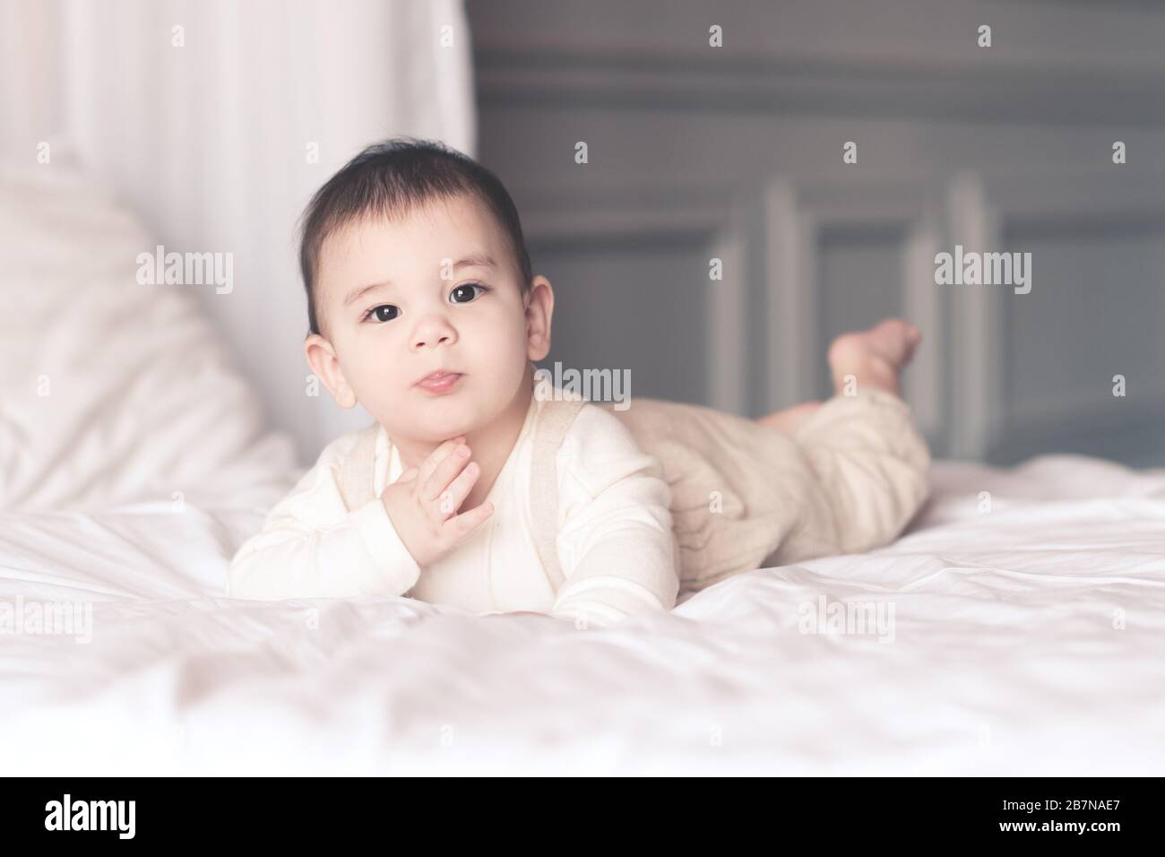 Bambino divertente sotto 1 anno che indossa pajama stylish sdraiato in primo piano letto. Guardando la fotocamera. Infanzia. Foto Stock