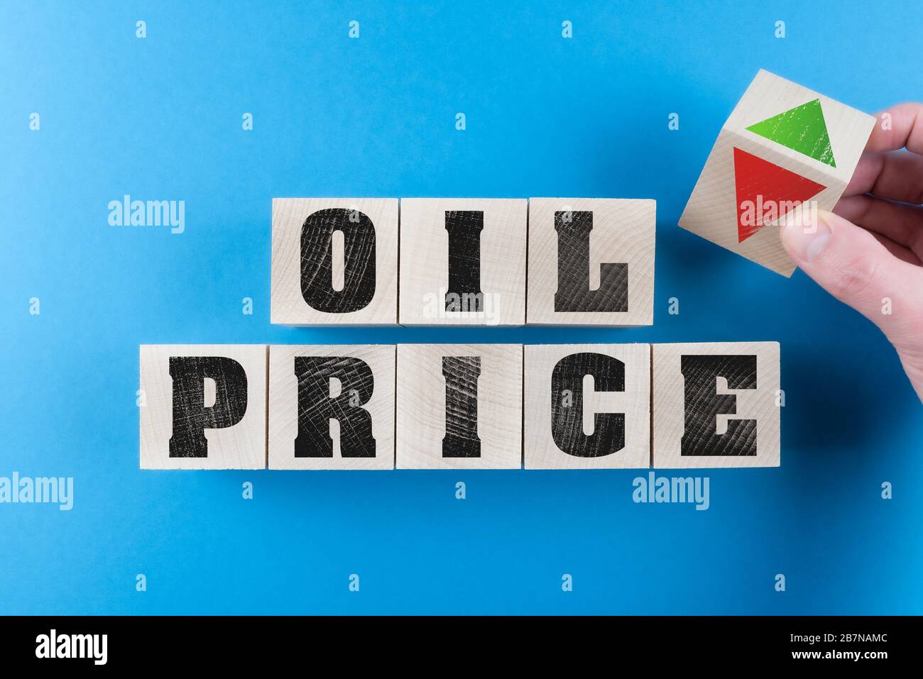 concetto di prezzi del petrolio in calo o in aumento con cubo di legno tornante a mano con simbolo di freccia rossa e verde Foto Stock