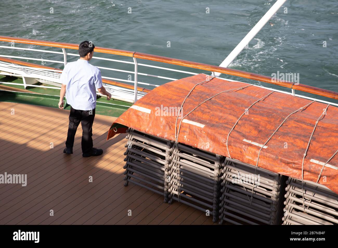 Un membro dell'equipaggio allontana i lettini a bordo della nave da crociera P&o Oceana Foto Stock