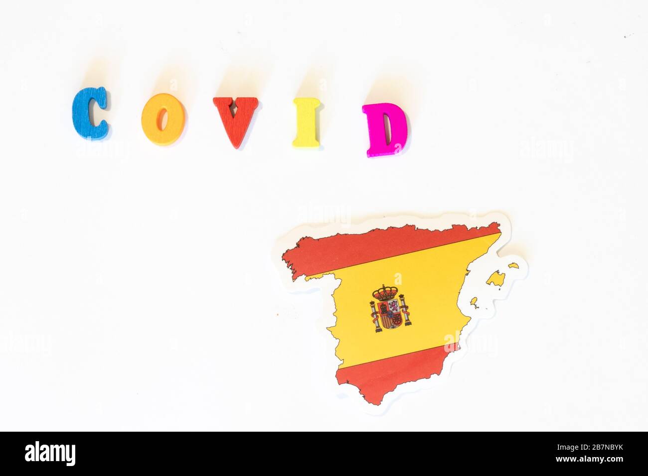 Spagna bandiera nazionale su sfondo bianco con l'iscrizione Covid fatta con la bacheca. Il coronavirus è un virus pandemico originario della Cina Foto Stock