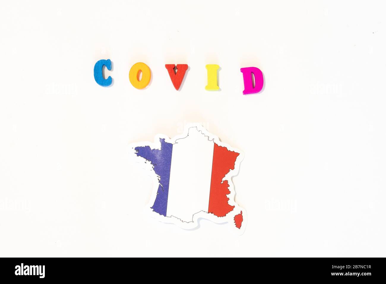 Bandiera nazionale francese su sfondo bianco con l'iscrizione Covid fatta con bacheca. Il coronavirus è un virus pandemico originario della Cina Foto Stock