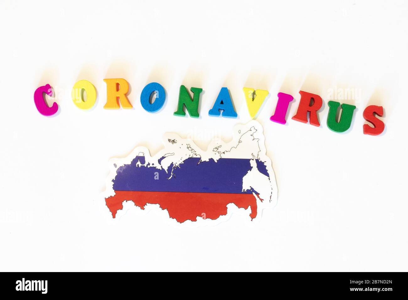 Bandiera nazionale russa su sfondo bianco con l'iscrizione Corona virus fatta con la bacheca delle lettere. Il coronavirus è un virus pandemico di origine Foto Stock