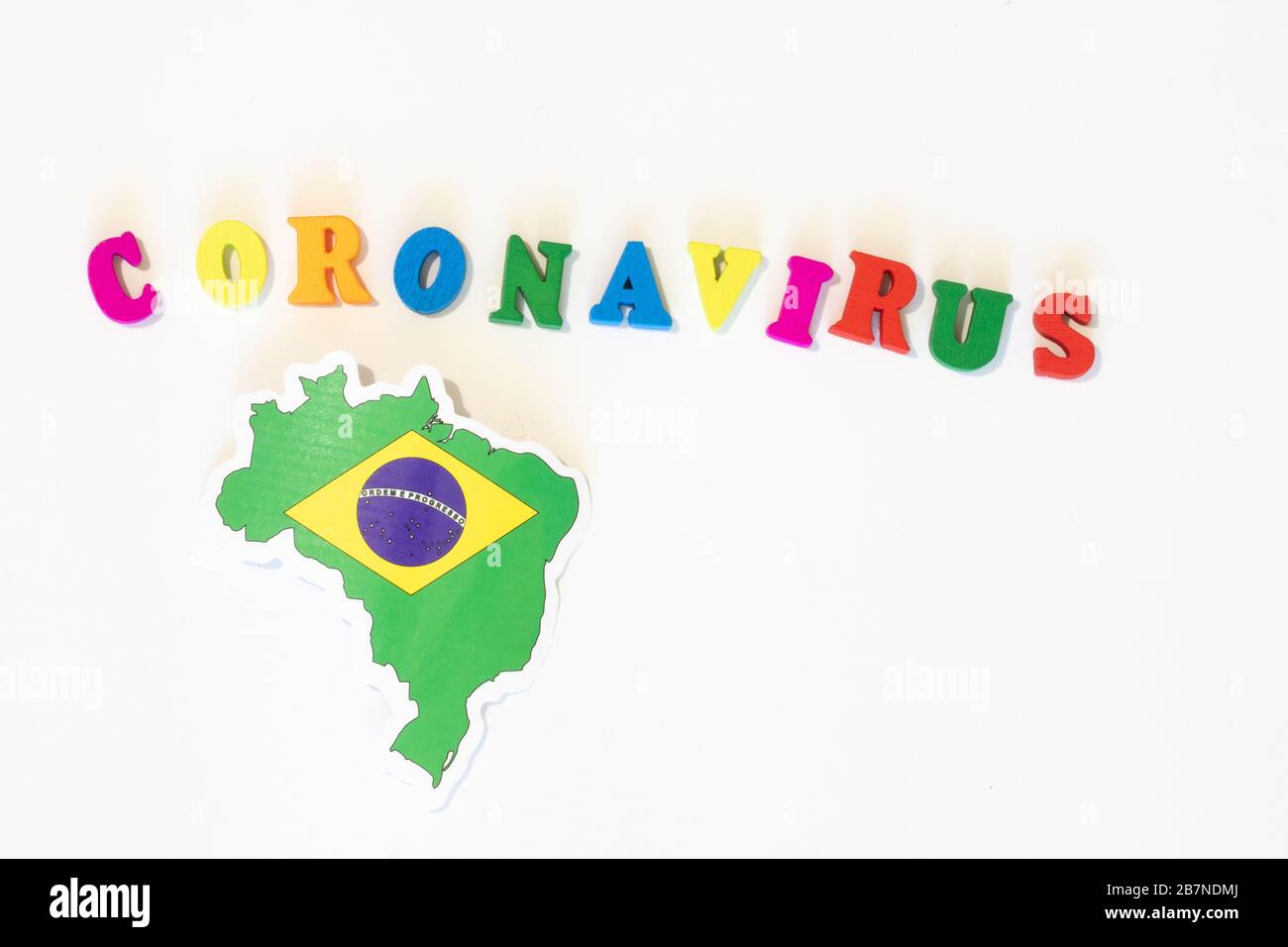 Bandiera nazionale brasiliana su sfondo bianco con l'iscrizione Corona virus fatta con letter board. Il coronavirus è un virus pandemico di origine Foto Stock