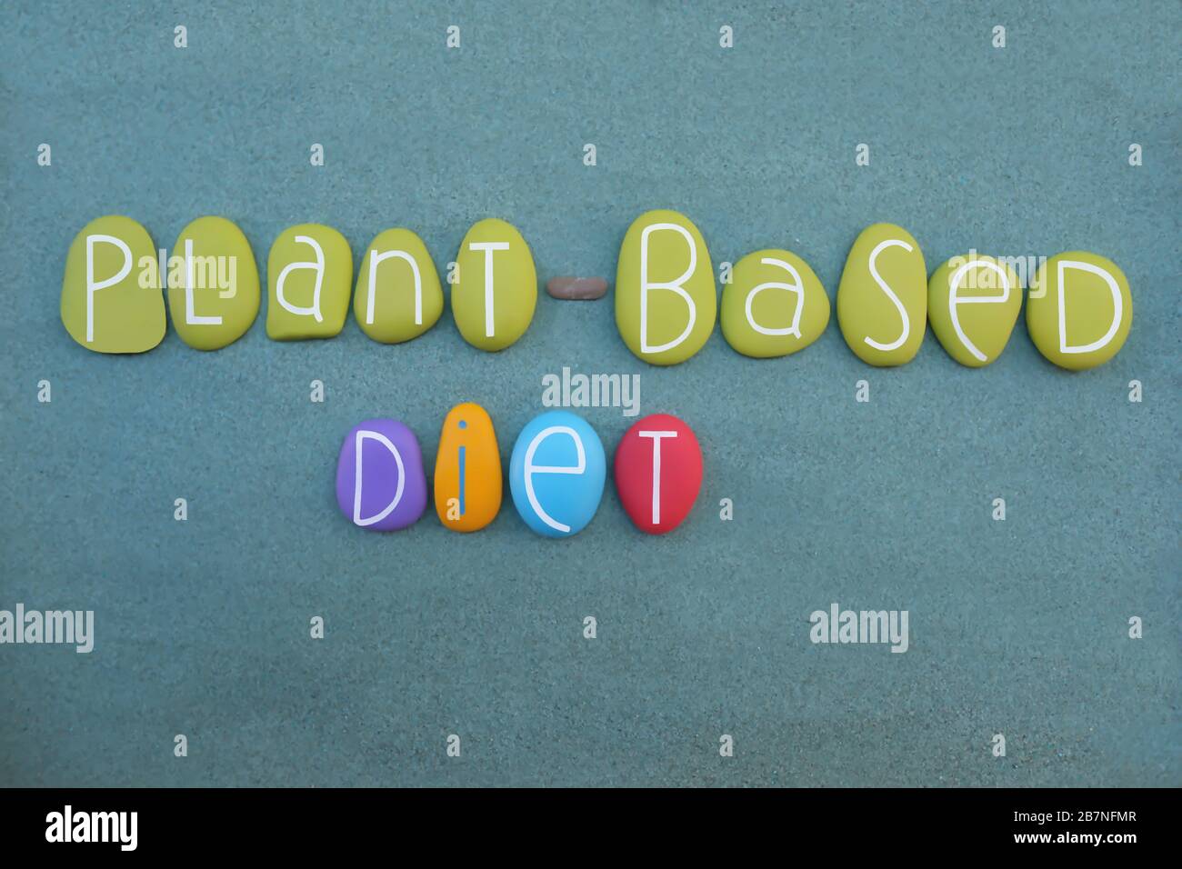 Pland basato testo di dieta composto con lettere di pietra multicolore su sabbia verde Foto Stock