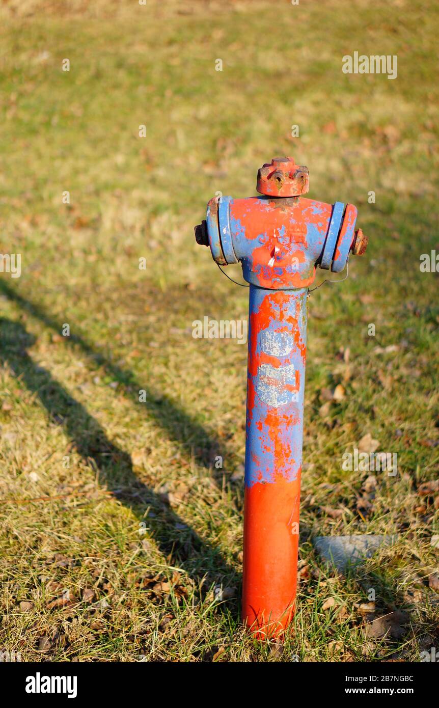 Primo piano verticale di un vecchio irrigatore ad acqua arrugginito un'area erbosa Foto Stock