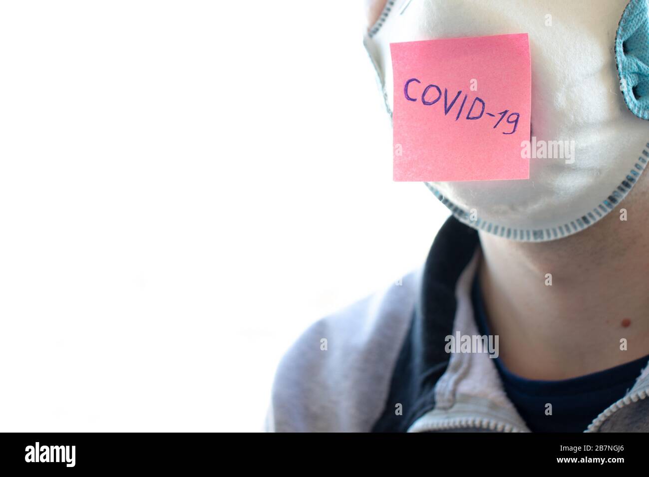 Uomo in maschera facciale respiratore e adesivo con Covid-19 parola sul viso. Il coronavirus è un virus pandemico. Protezione da malattie e batteri Foto Stock