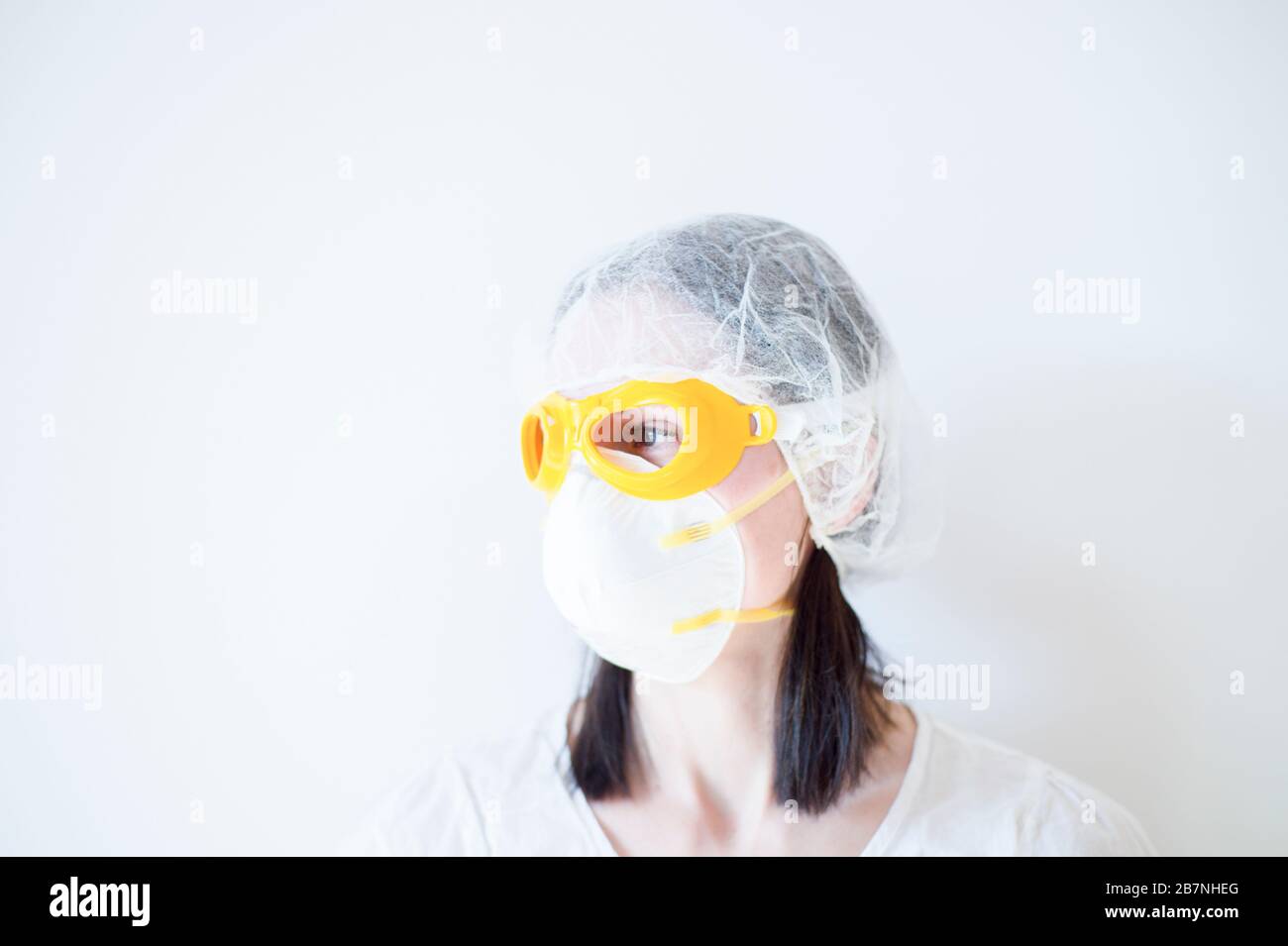 Dottore Donna in maschera utilizzando stetoscopio Foto Stock